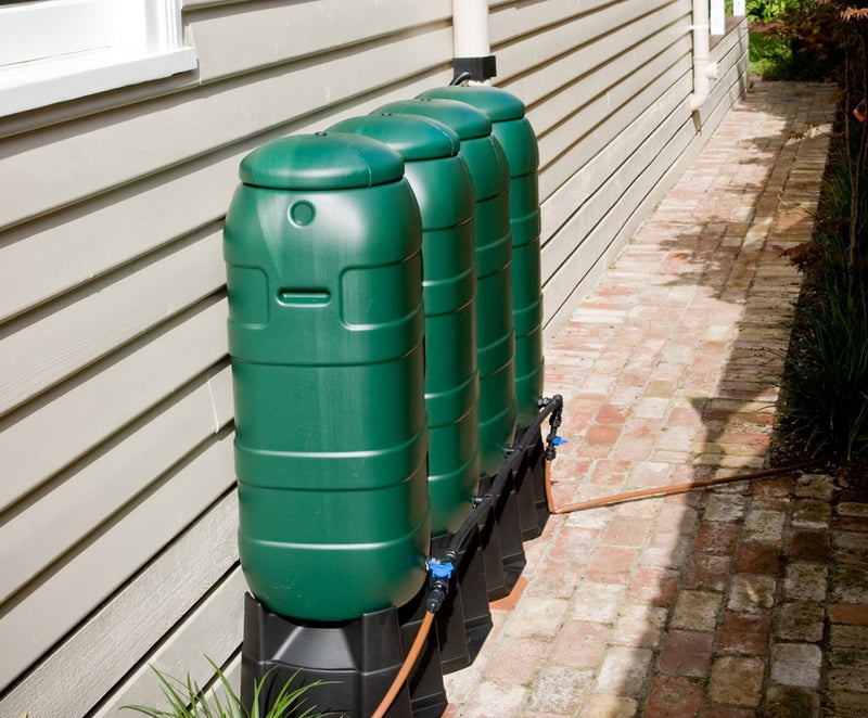 Four 100 litre mini water tanks against a wall